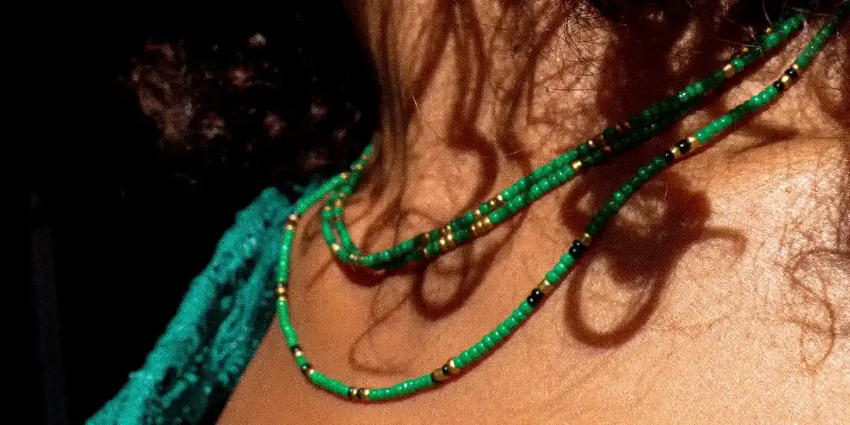 Livraison offert dès 60€ d'achat Une femme noir porte sensuellement un collier en coquillage de cauri et micro macramé