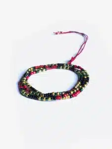 Bracelet artisanal multi-rangs composé de petites perles rouges, vertes, noires et dorées, monté sur un cordon ajustable rouge, présenté sur un fond blanc.
