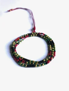 Bracelet artisanal multi-rangs composé de petites perles rouges, vertes, noires et dorées, monté sur un cordon ajustable rouge, présenté sur un fond blanc.